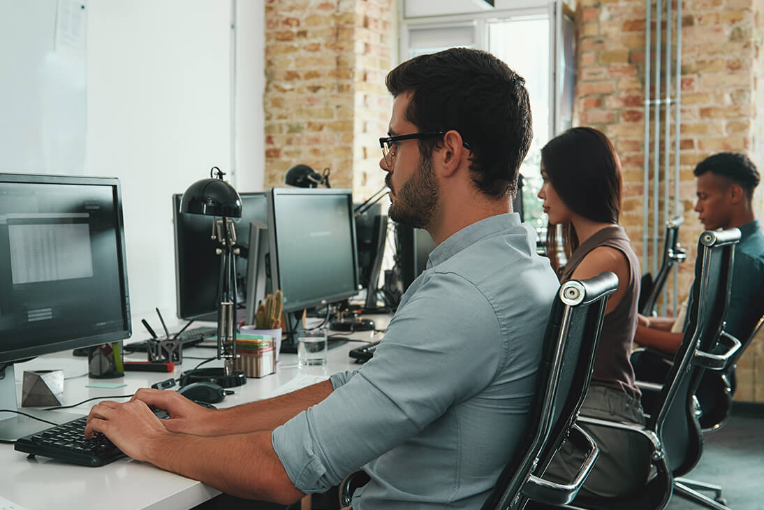 A number of people working on computers in a office setting